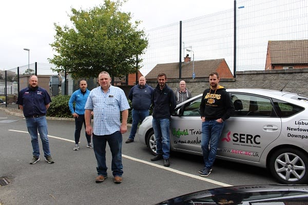 Seven students from automotive industry with SERC Training Consultant Alan Kerr standing in front of SERC branded Hybrid car.